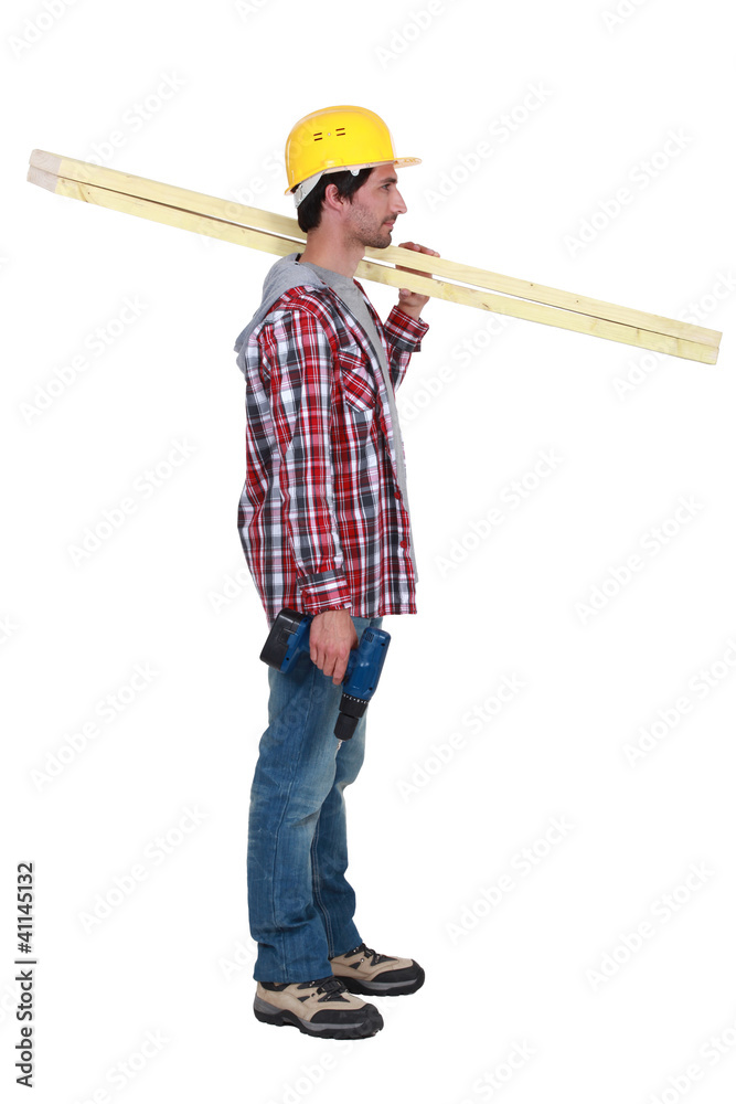 carpenter standing in profile holding ruler over his shoulder carpenter standing in profile holding ruler over his shoulder