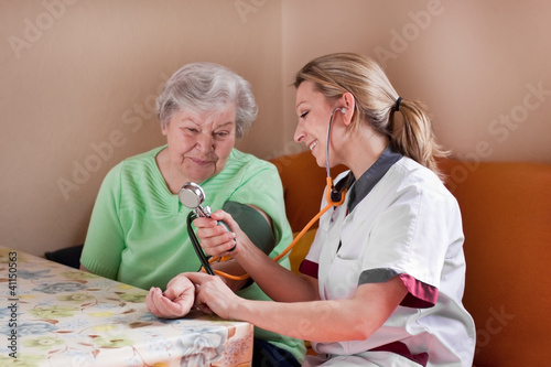 Altenpflegerin misst Blutdruck bei Seniorin photo