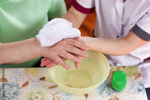 Altenpflegerin wäscht Patientin die Hände photo