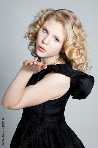 Young blonde girl blowing a kiss and posing in studio