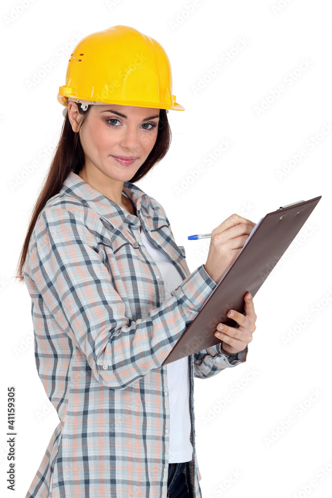 Female construction worker writing on her clipboard. Female construction worker writing on her clipboard.