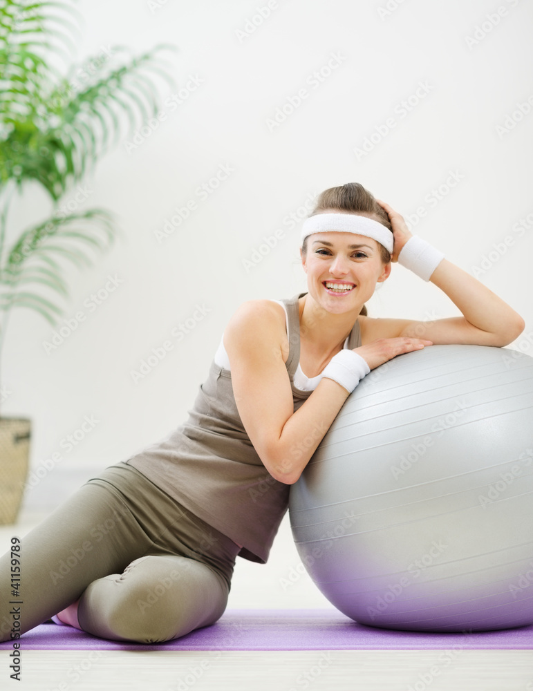 Happy woman sitting near fitness ball Happy woman sitting near fitness ball