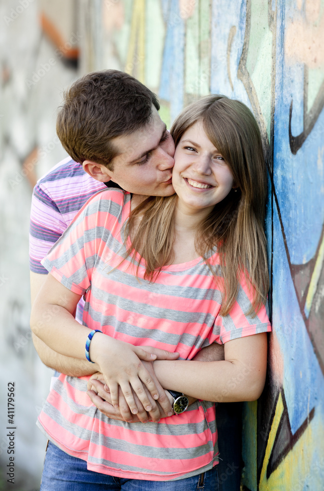 Young couple kissing near graffiti background. Young couple kissing near graffiti background.