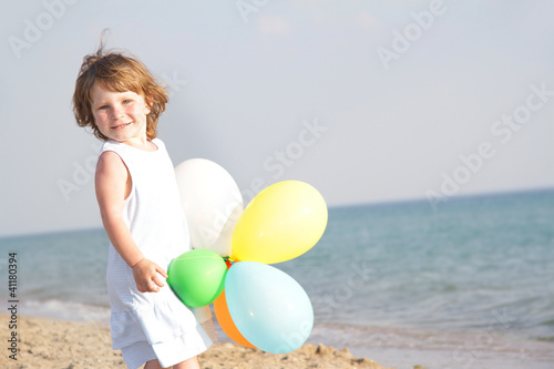 young happy girl with colorful balloons on sea background