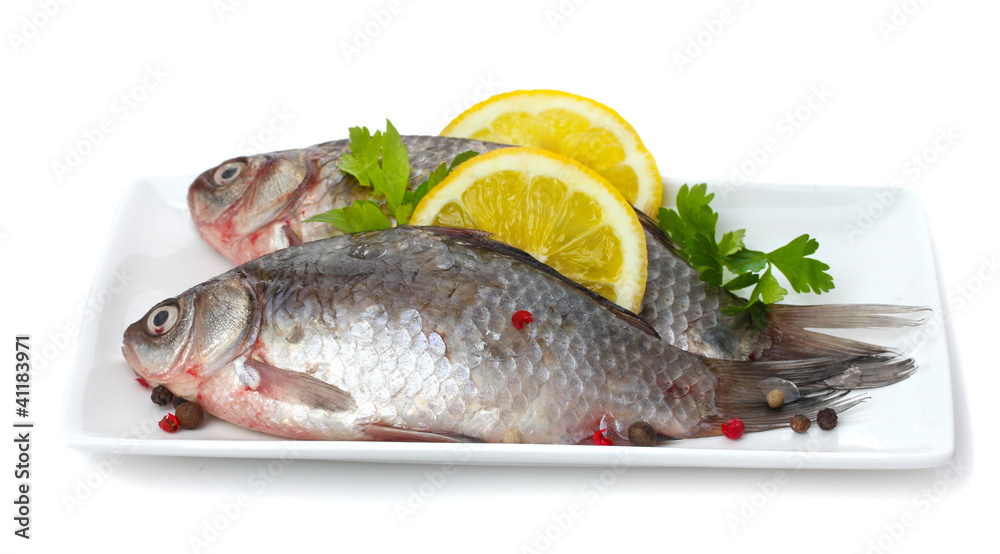Fresh fishes with lemon and parsley on plate isolated on white Fresh fishes with lemon and parsley on plate isolated on white