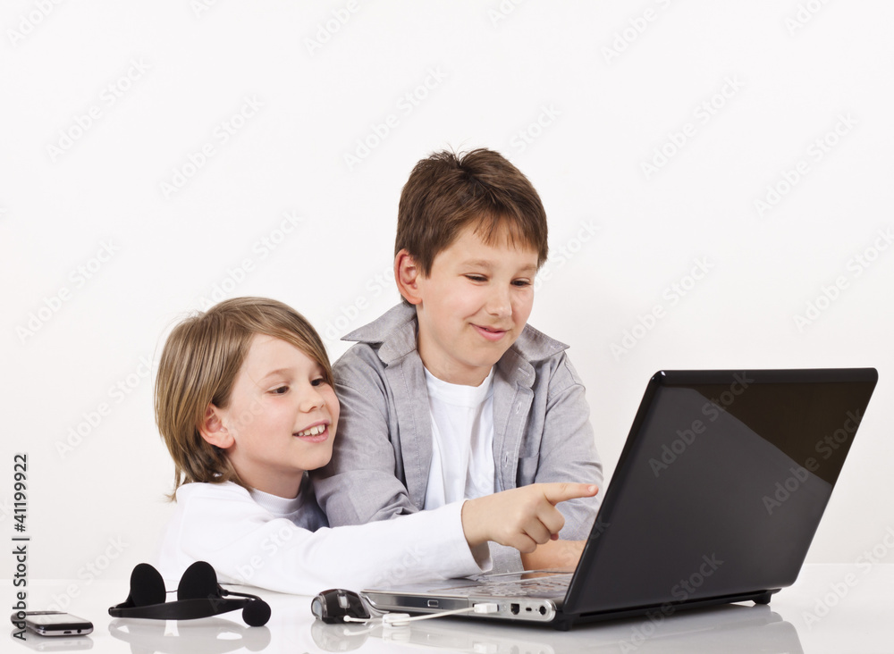 Two cheerful boys looking something on lap top Two cheerful boys looking something on lap top