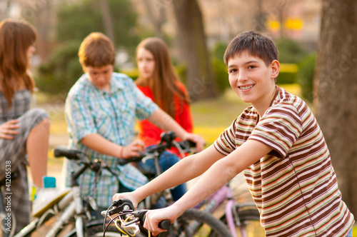 Happy teenage boy spending time with his friends riding bicycles