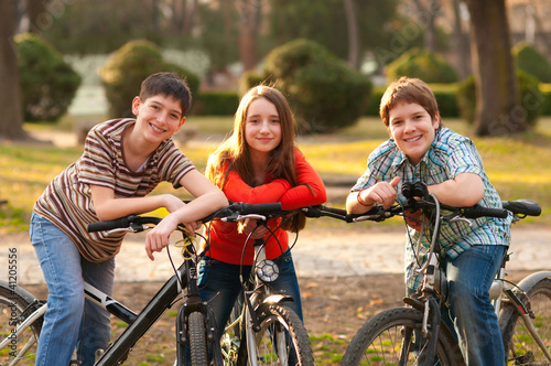 Two teenage boys and one teenage girl having fun on bicycles