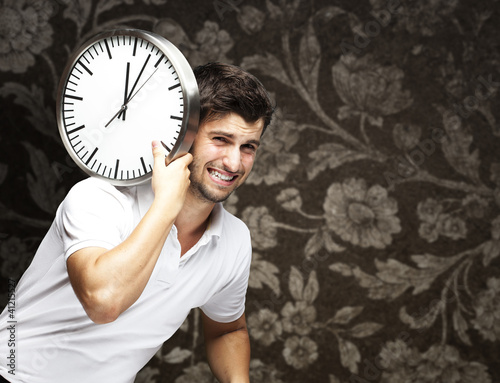 portrait of a handsome young man carrying a clock against a vint photo