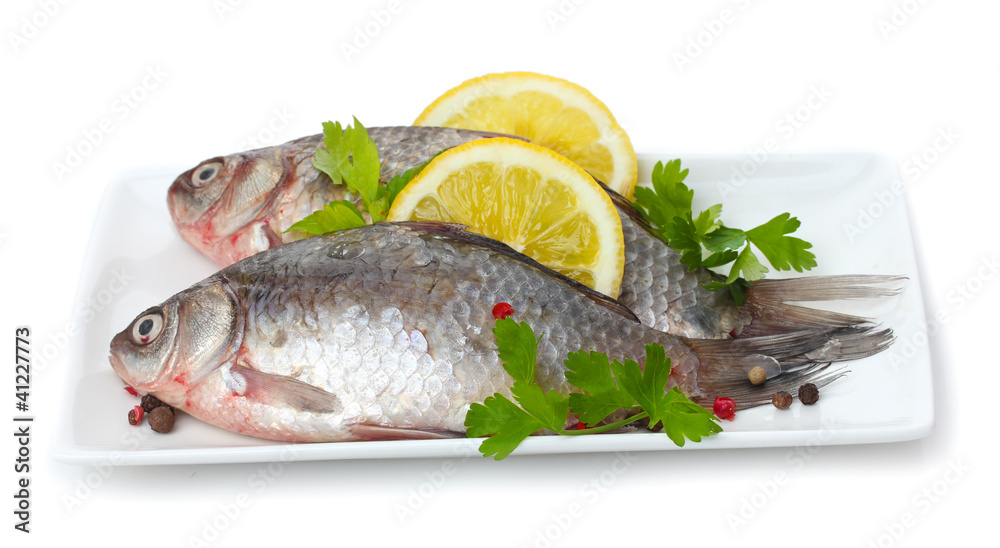 Fresh fishes with lemon and parsley on plate isolated on white Fresh fishes with lemon and parsley on plate isolated on white
