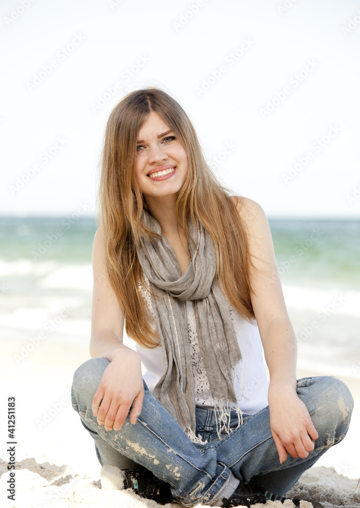 Funny teen girl sitting near the sea.
