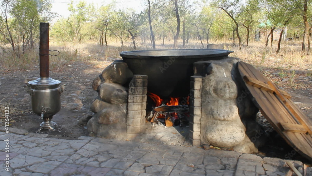 Kettle with cooking meat over burning campfire. Kettle with cooking meat over burning campfire.