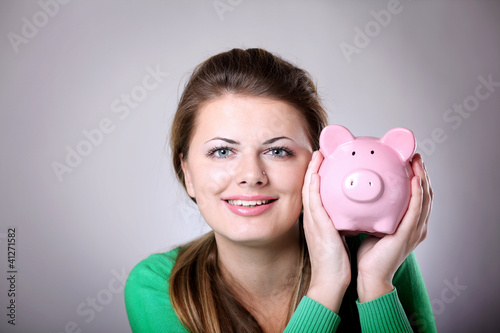 Young woman showing her pink piggy bank