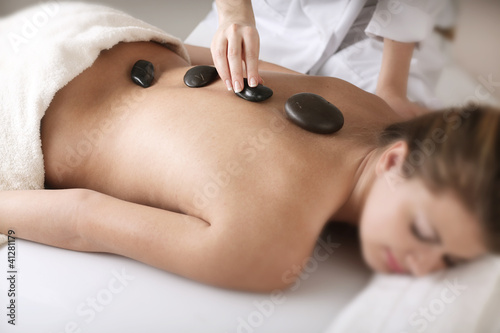 Young woman enjoying a back massage with hot stone in a spa