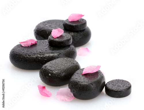 Spa stones with drops and pink petals isolated on white.
