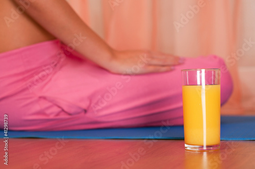 Glass of orange juice in front of sporty woman