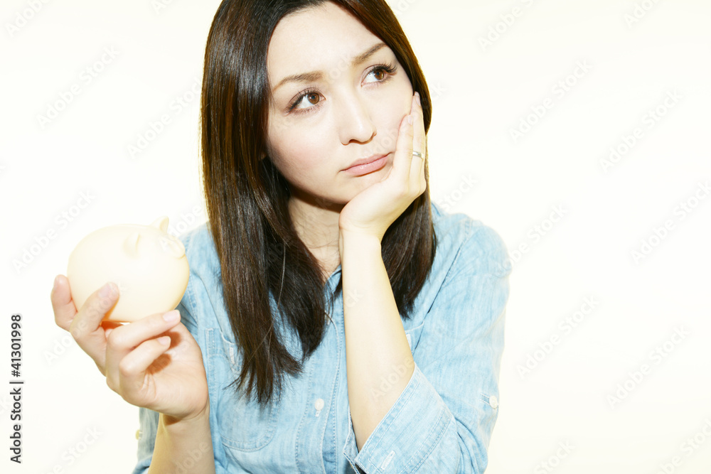 貯金箱を持ち悩んでいるオフィスレディー