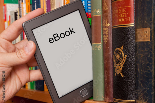 eBook vs Buch, e-Reader aus einem Bücherregal ziehen photo