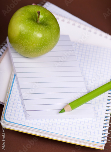 green apple and pencil on empty page of a notebook