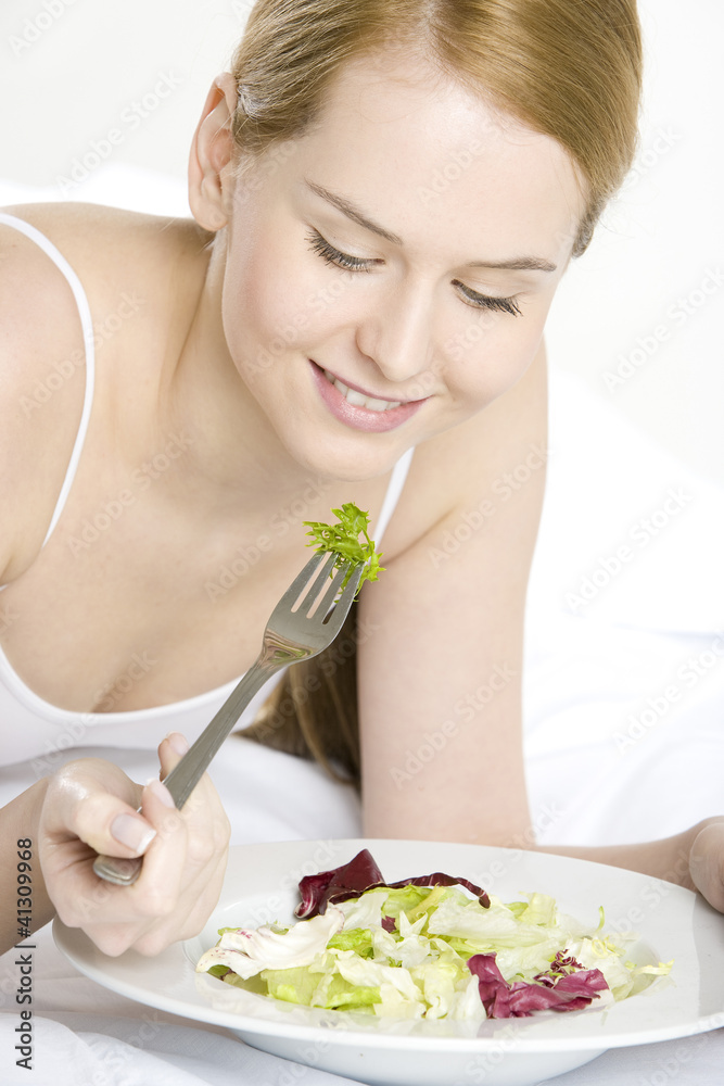 portrait of lying down woman eating salad portrait of lying down woman eating salad