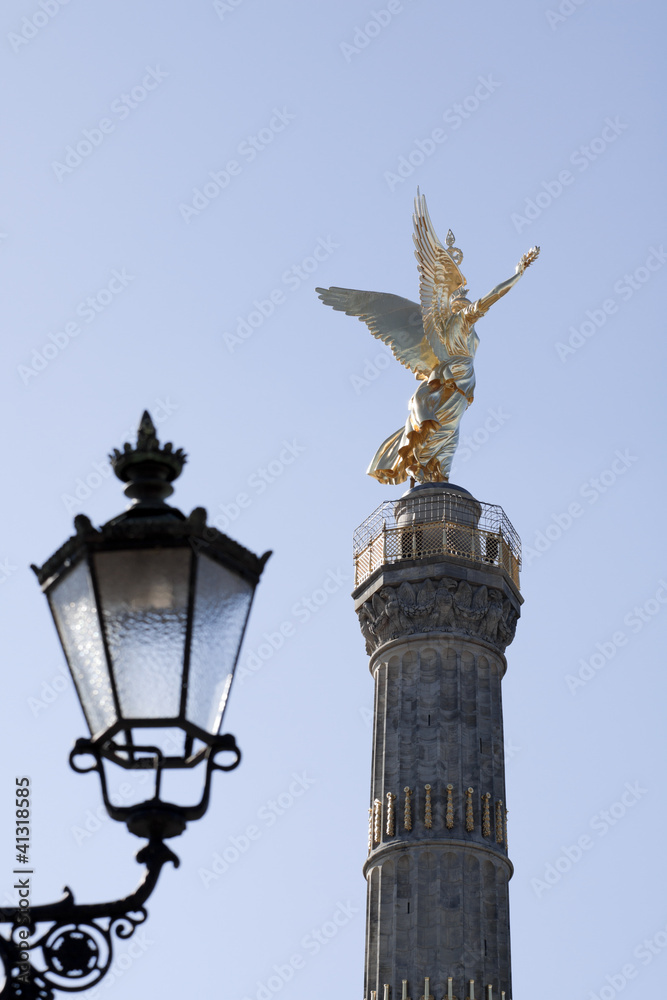 Back view in vertical composition of The Golden Angel on top of the Victory Column reflects the sunlight; it is a monument located in Berlin, in center of the 