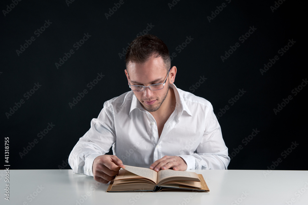 Young man reading a book against black background. Young man reading a book against black background.