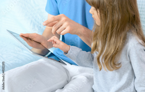 Father with daughter playing on digital tablet