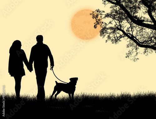 Silhouette of a couple walking their dog on sunset
