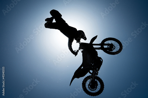 Silhouette of FMX rider against the sun on the sky