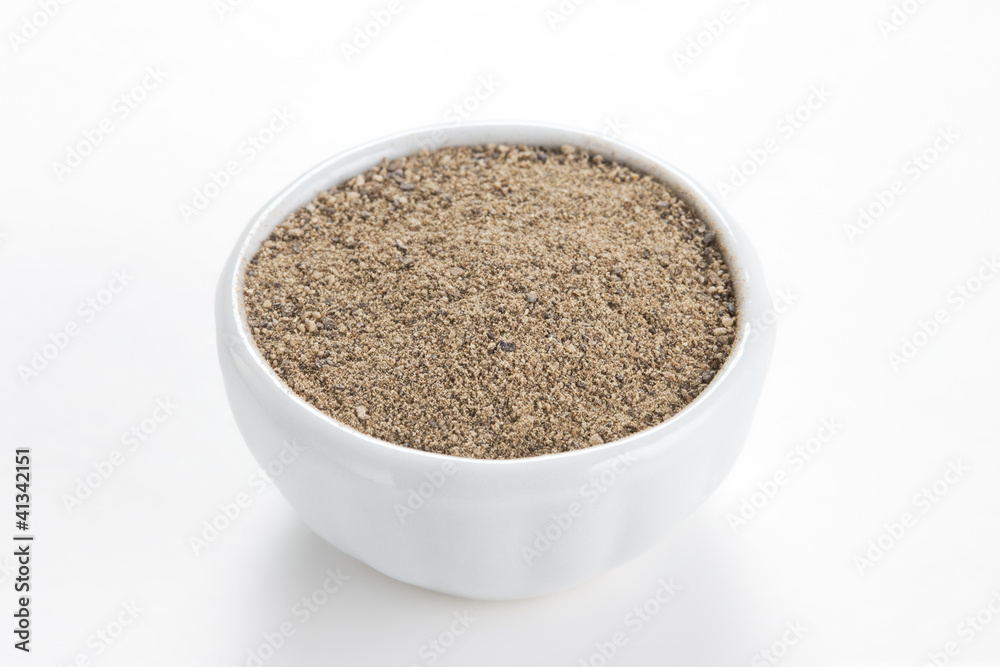 Black pepper ground (Piper nigrum) in a white bowl on white back Black pepper ground (Piper nigrum) in a white bowl on white back