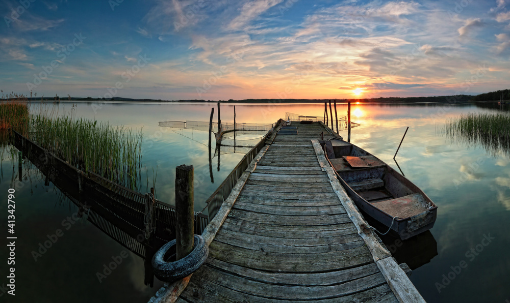 Steg mit Boot im Sonnenuntergang