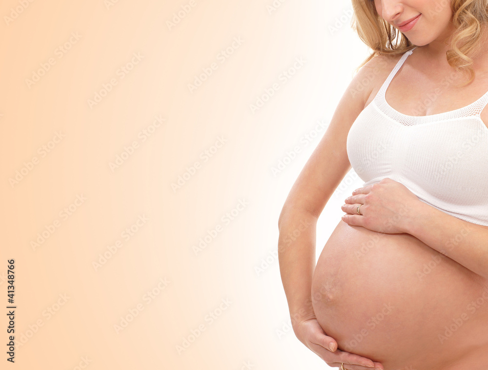 A young blond pregnant Caucasian woman in a white bra A young blond pregnant Caucasian woman in a white bra
