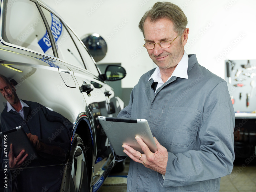 Master mechanic in a garage working with touchpad