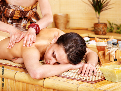 White woman getting massage in bamboo spa.