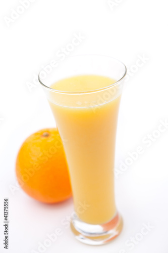 Orange behind a full glass of orange juice