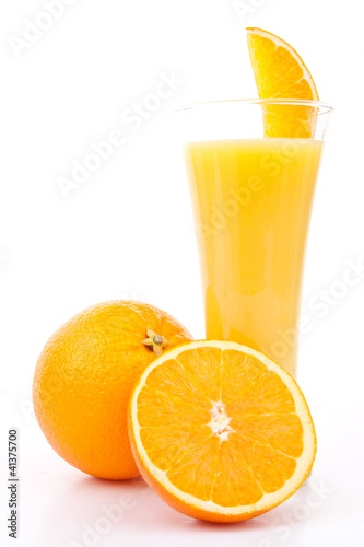 One orange and a half next to a glass of orange juice