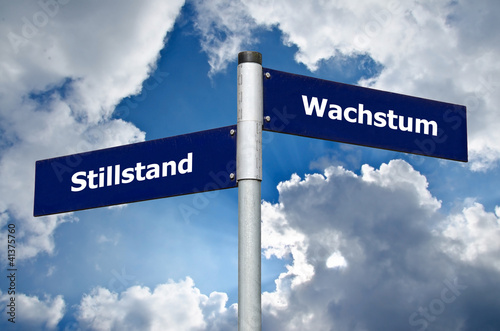 Foto Straßenschild vor bewölktem Himmel welches den Zielkonflikt zwischen 'Stillstand