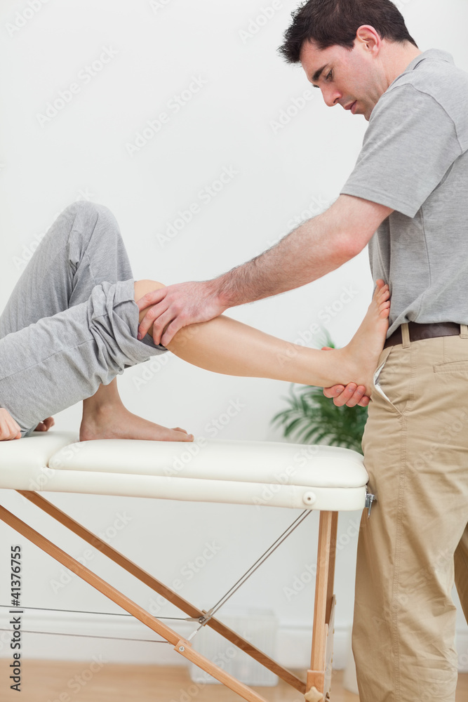 Brunette physiotherapist stretching a foot Brunette physiotherapist stretching a foot