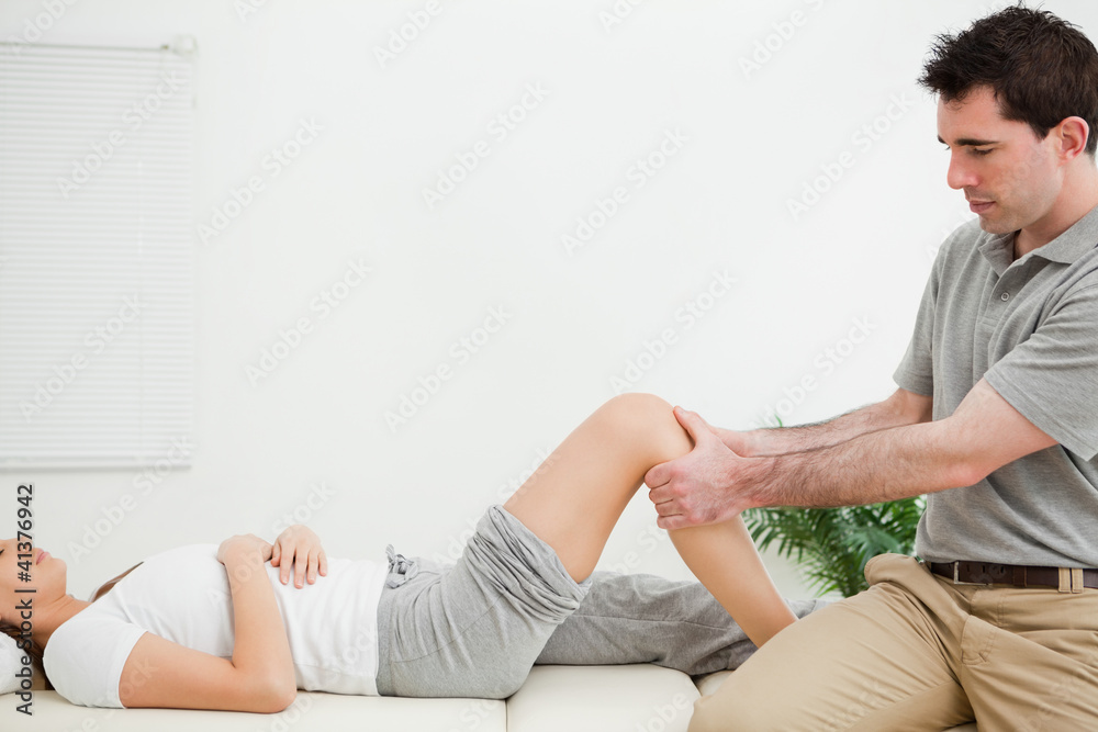 Physiotherapist sitting while massaging a knee Physiotherapist sitting while massaging a knee