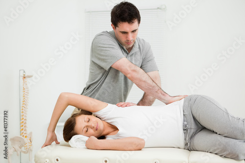 Osteopath crossing his arms while massaging a woman
