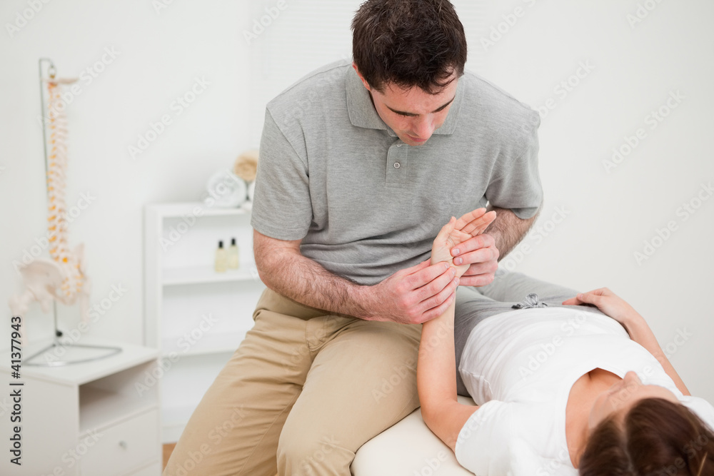 Serious physiotherapist holding the hand of a woman Serious physiotherapist holding the hand of a woman