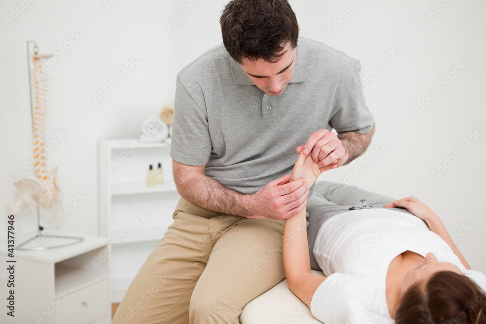 Physiotherapist looking at the wrist of a patient Physiotherapist looking at the wrist of a patient