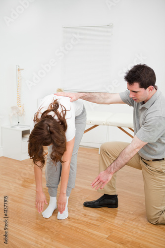 Doctor looking at a patient who is doing stretching exercises
