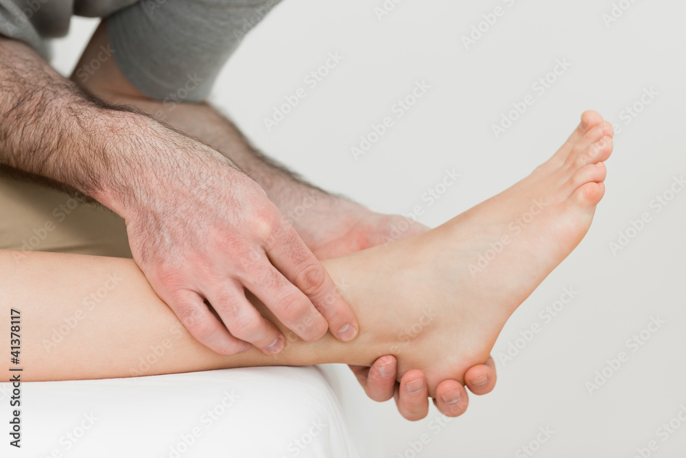 Physiotherapist working on the shin bone of a patient Physiotherapist working on the shin bone of a patient