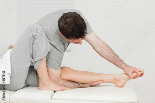 Brunette osteopath stretching a foot © WavebreakmediaMicro