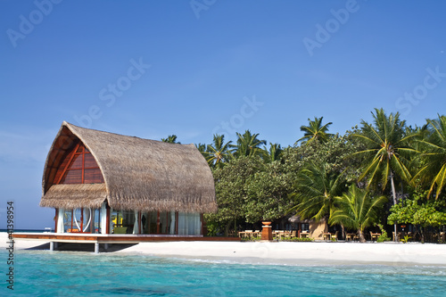 Landscape photo of beach house in Maldive ocean with blue sky
