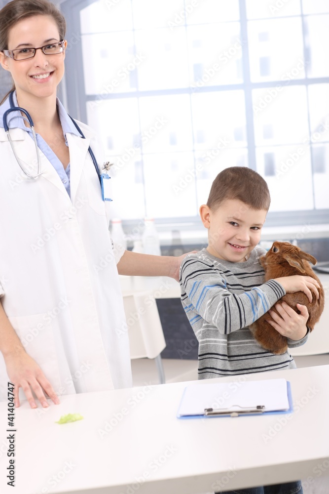 Fototapeta premium Smiling kid with pet rabbit at veterinary