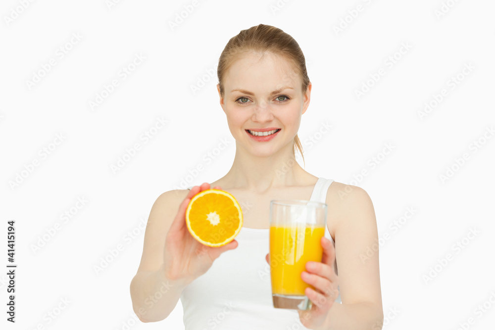 Cheerful woman presenting an orange while holding a glass Cheerful woman presenting an orange while holding a glass