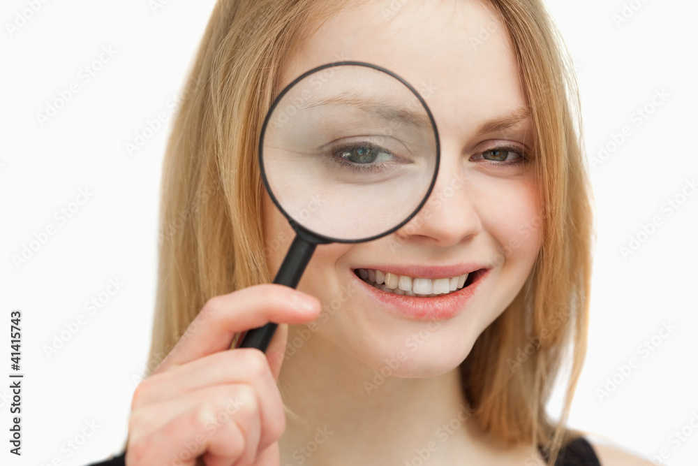 Woman placing a magnifying glass on her eye Woman placing a magnifying glass on her eye