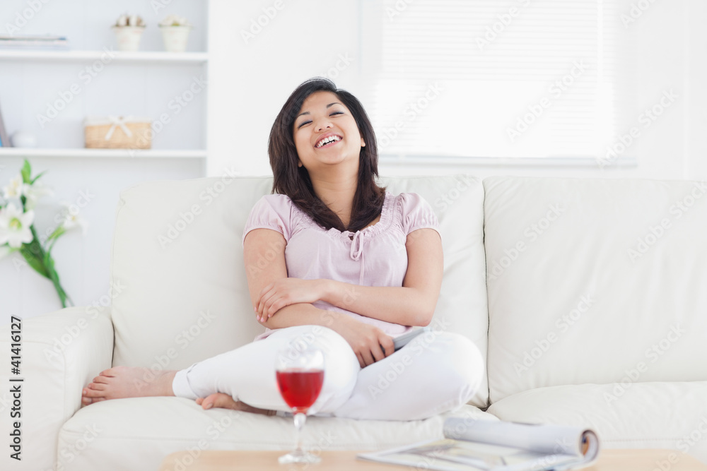 Woman laughing while resting on a sofa Woman laughing while resting on a sofa